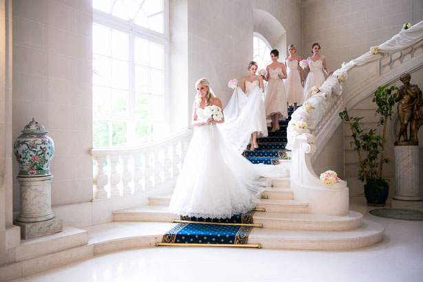 Brides descends beatuiful chateau staircase with bridesmaids