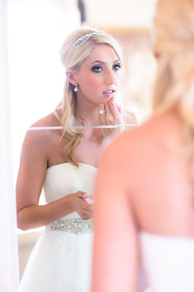 Bride retouches lipstick in mirror