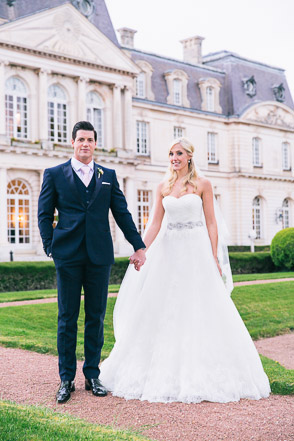 Bride and groom hold hands at chateau in France