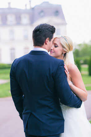 Bride and groom embrace in front of French chateau
