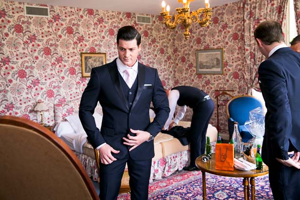 Groom arranges tux in french chateau bedroom
