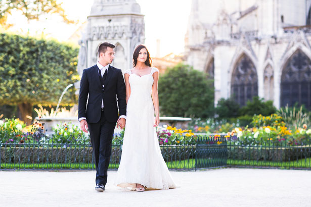 Wedding couple walks by Notre Dame flower garden