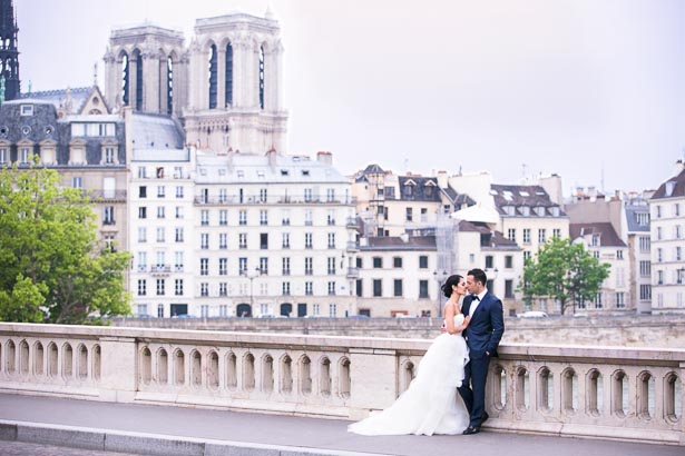 Paris Skyline Behind Bride and Groom on Bridge
