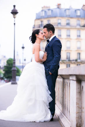 Bride Kissing Groom with Paris Buildings and Lampposts in Background
