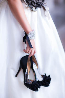 Bride in Gown Holding Black Wedding Shoes