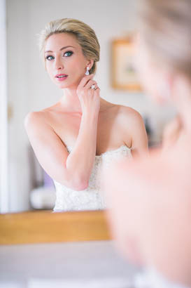 Bride Adjusting Earrings in Mirror